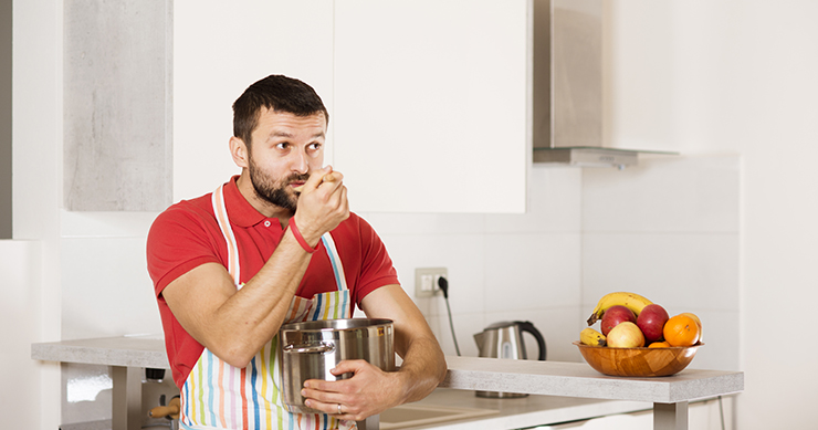 man nibbling on ingredients while cooking