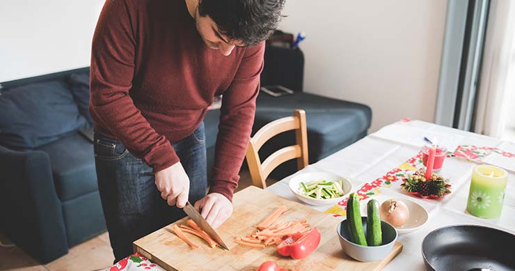 man with red long sleeves shirt chopping red pepper