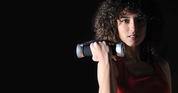 girl with balck background holding a dumbbell