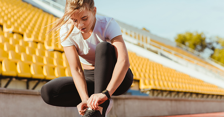 Young girl lacing up her shoes before running