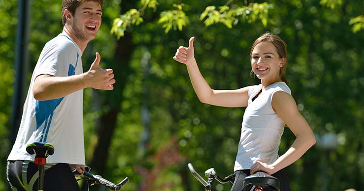 man and woman thumbs up while riding their bike in the street