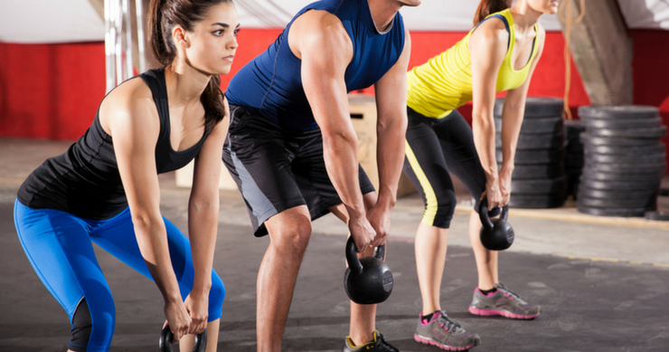 two girls and one guy exercising with kettlebells