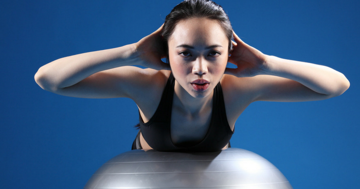 fit girl exercising using vestibular ball